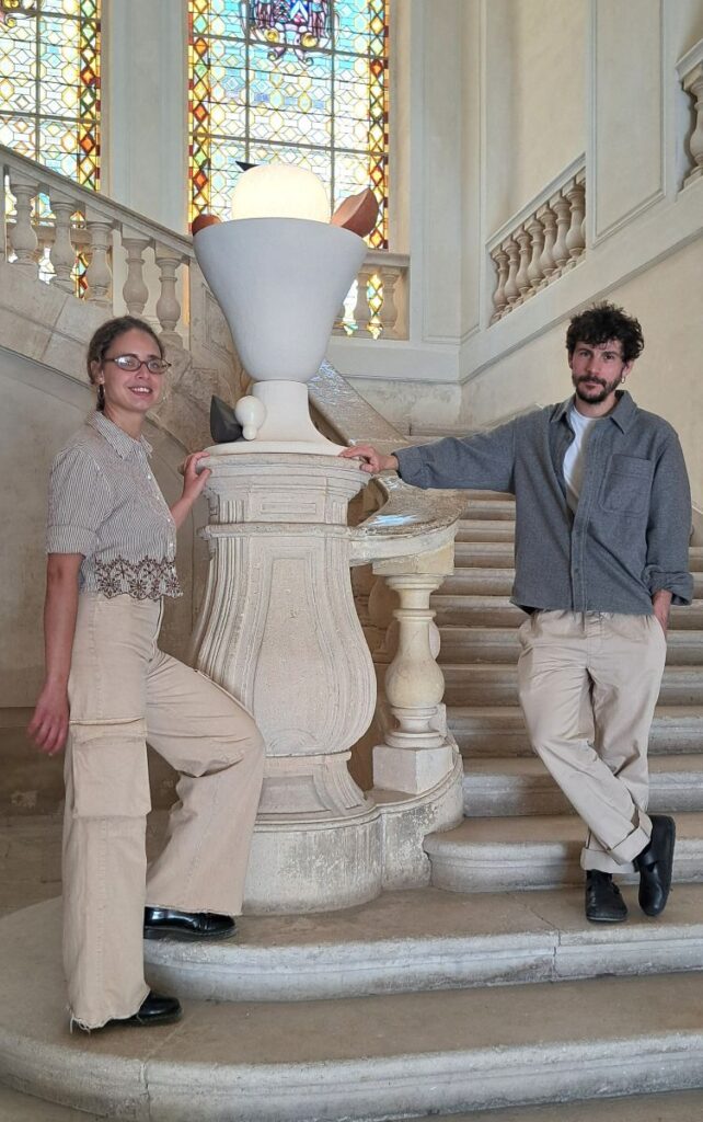 Designers and plastic artists Baptiste Sévin and Jaïna Ennequin on the grand staircase whose first newel serves as pedestal for one of their works. Photo © GLK.