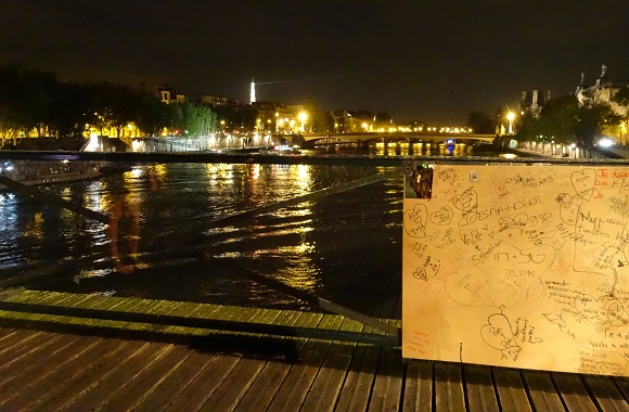 Paris by night on the Pont des Arts with glass panels next to wood panel protecting a portion damanged by locks. Photo GLK.